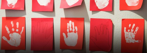 Barns handavtryck på röda papper uppsatta på en vägg | © Maskot / Getty Images